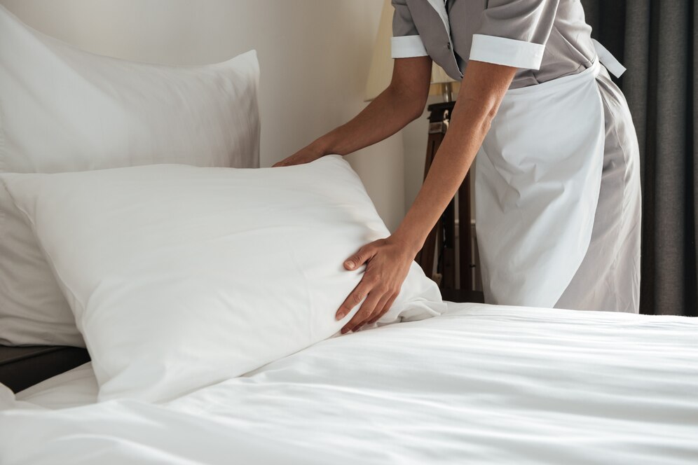Клинер застилает постель в отеле